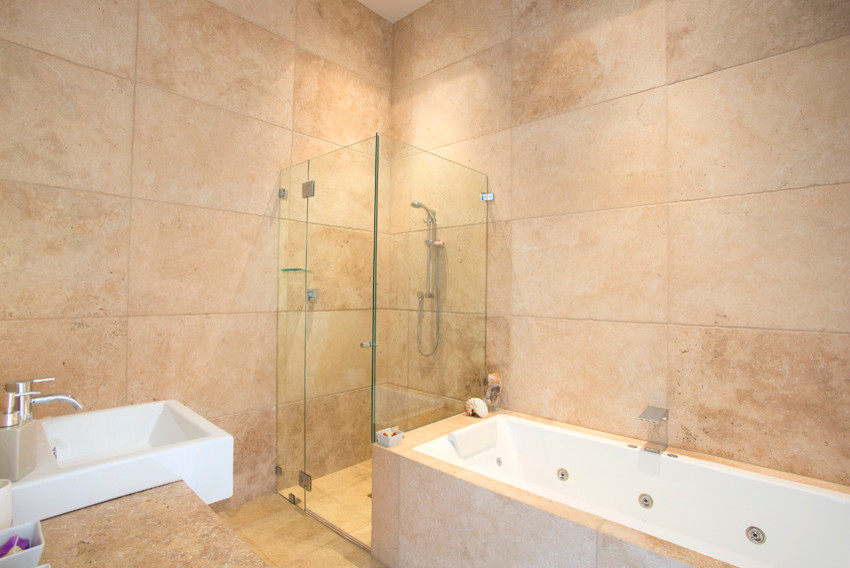Inspiration for a large country master bathroom in Sydney with white cabinets, a hot tub, a corner shower, a two-piece toilet, stone tile, travertine floors, solid surface benchtops, flat-panel cabinets, beige tile, beige walls, a trough sink, beige floor, a hinged shower door and beige benchtops.
