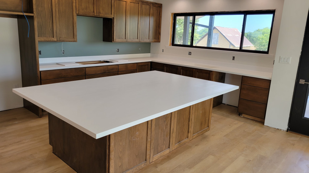 Kitchen - l-shaped kitchen idea with an integrated sink, solid surface countertops and white countertops