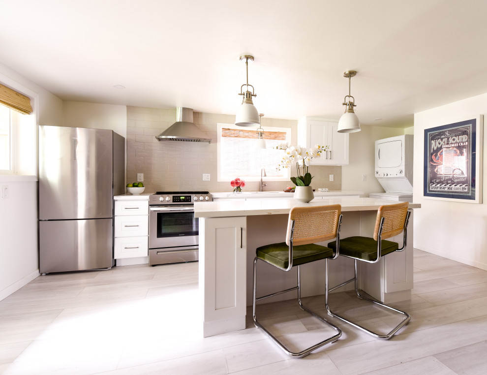 Example of a transitional galley vinyl floor and gray floor kitchen design in Seattle with an undermount sink, shaker cabinets, white cabinets, quartzite countertops, gray backsplash, subway tile backsplash, stainless steel appliances, an island and white countertops