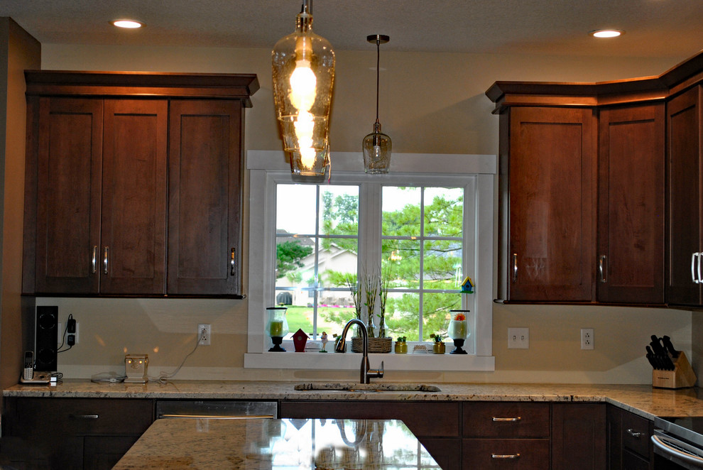 Kitchen - brown floor kitchen idea with brown cabinets, stainless steel appliances, an island and beige countertops