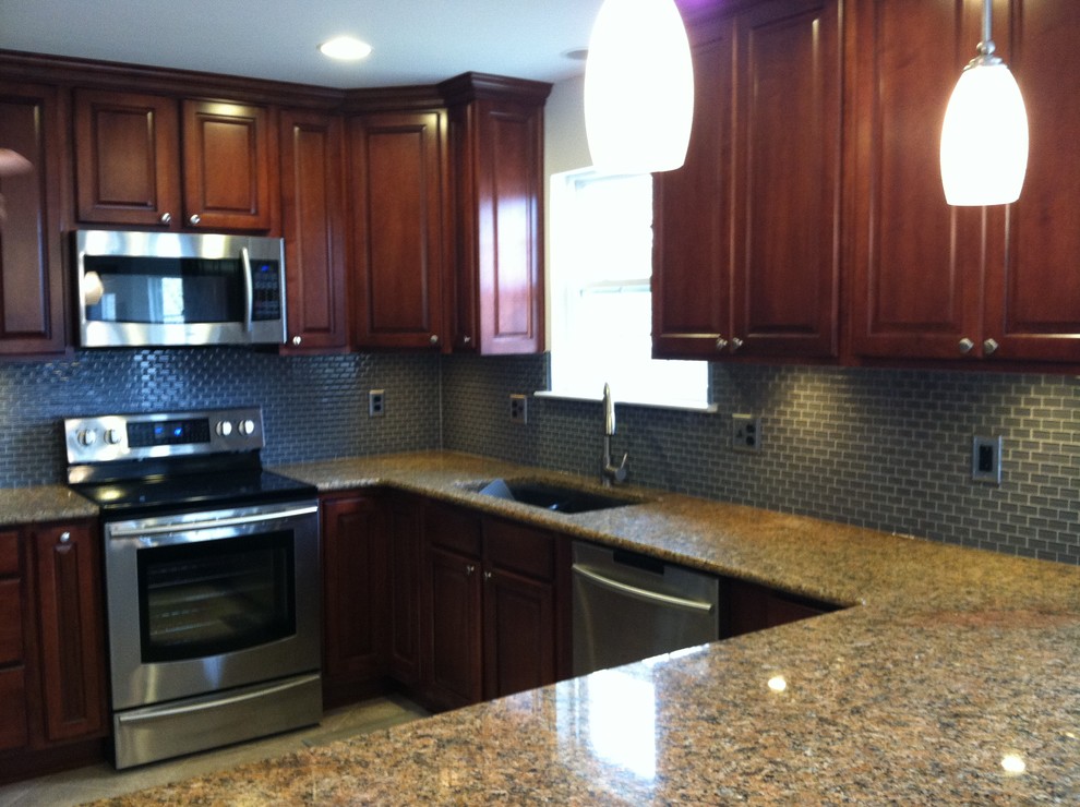 Example of a large transitional u-shaped ceramic tile and beige floor enclosed kitchen design with an undermount sink, raised-panel cabinets, dark wood cabinets, blue backsplash, ceramic backsplash, stainless steel appliances, a peninsula and granite countertops