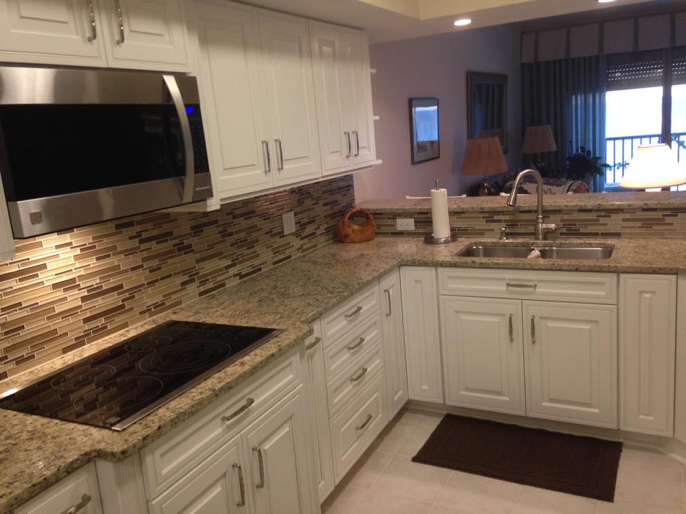 Open concept kitchen - mid-sized l-shaped ceramic tile open concept kitchen idea in Miami with an undermount sink, raised-panel cabinets, white cabinets, granite countertops, brown backsplash, glass tile backsplash, stainless steel appliances and a peninsula