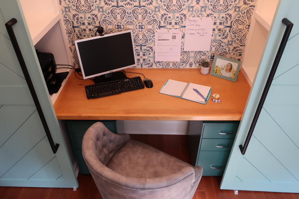 Exemple d'un petit bureau tendance avec un mur bleu, un bureau intégré, du papier peint, un sol en bois brun et un sol marron.