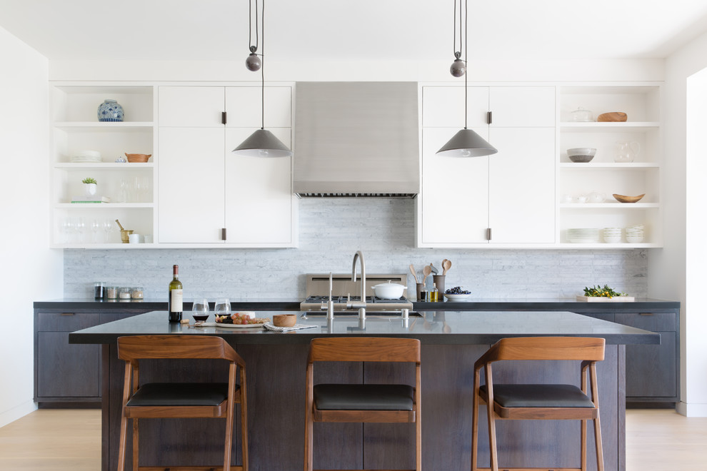 Photo of a contemporary kitchen in San Francisco with a drop-in sink, flat-panel cabinets, white cabinets, grey splashback, stainless steel appliances, with island and beige floor.