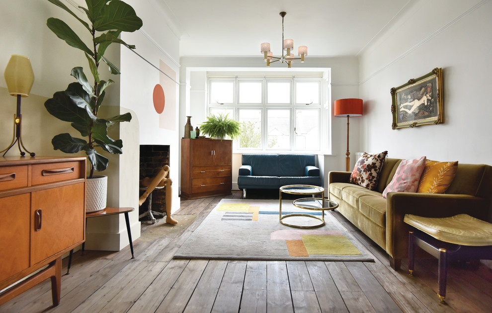 Design ideas for a mid-sized eclectic open concept living room in London with white walls, a concealed tv, medium hardwood floors, a standard fireplace and brown floor.