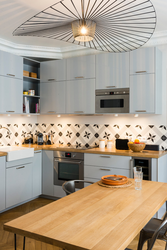 This is an example of a mid-sized contemporary l-shaped eat-in kitchen in Paris with flat-panel cabinets and grey cabinets.