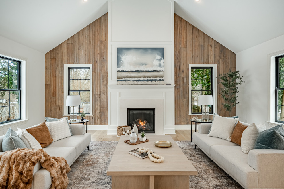 Transitional open concept light wood floor, beige floor and vaulted ceiling living room photo in Philadelphia with white walls, a standard fireplace and a stone fireplace