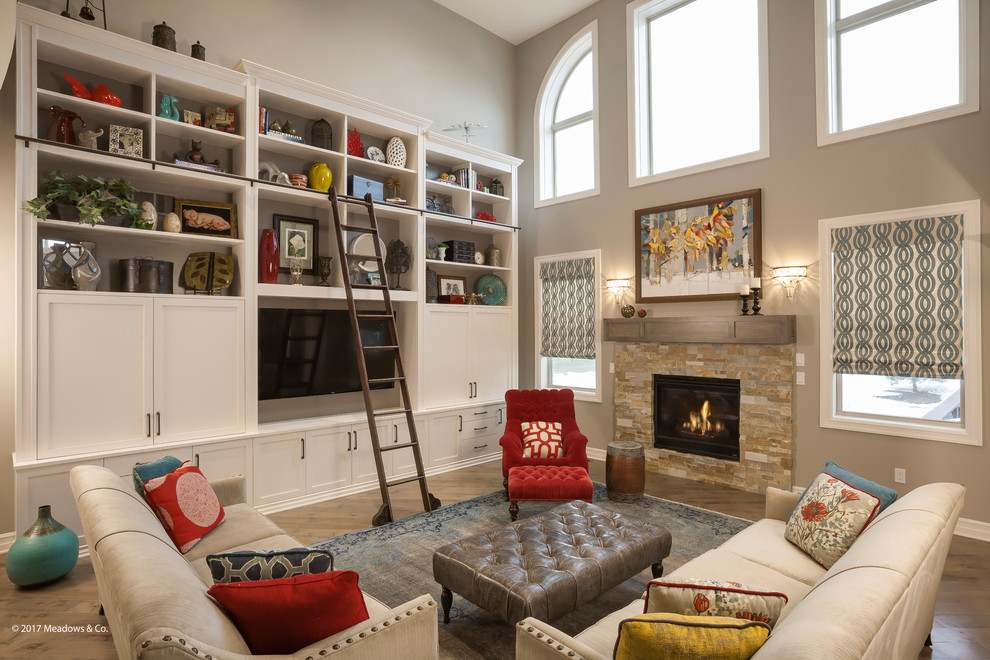 This is an example of a large transitional open concept living room in Detroit with grey walls, light hardwood floors, a standard fireplace, a tile fireplace surround, a library, a built-in media wall, grey floor and recessed.