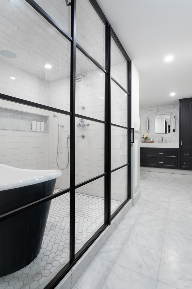Inspiration for a large transitional master bathroom in New York with shaker cabinets, black cabinets, a freestanding tub, a shower/bathtub combo, white tile, ceramic tile, white walls, marble floors, an undermount sink, quartzite benchtops, grey floor, a hinged shower door, grey benchtops, a double vanity and a built-in vanity.