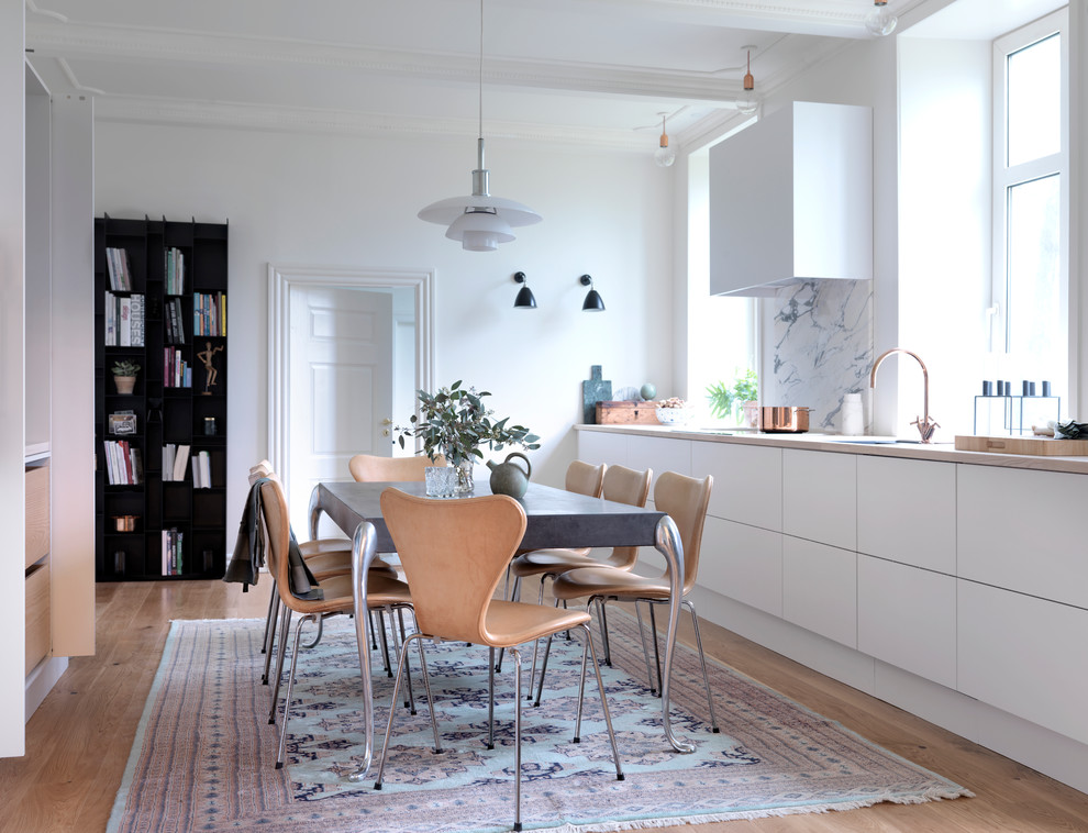 This is an example of a mid-sized scandinavian single-wall eat-in kitchen in Esbjerg with flat-panel cabinets, white cabinets, light hardwood floors, no island, wood benchtops, multi-coloured splashback and porcelain splashback.