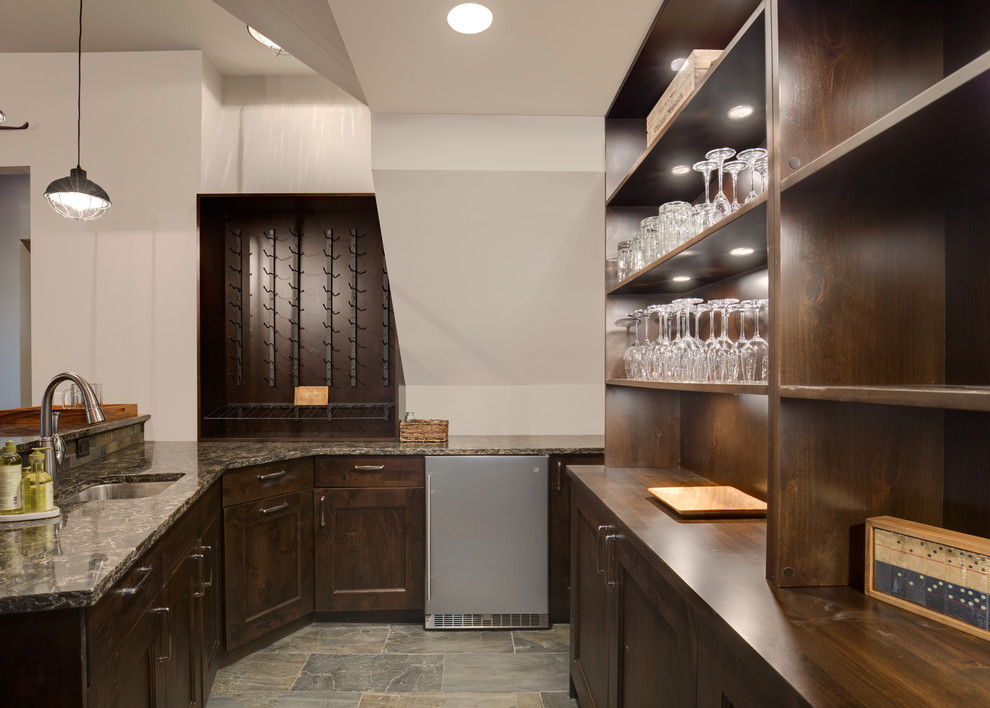 Photo of a mid-sized country u-shaped wet bar in Other with an undermount sink, shaker cabinets, medium wood cabinets, quartz benchtops, multi-coloured splashback, slate splashback, vinyl floors and brown floor.