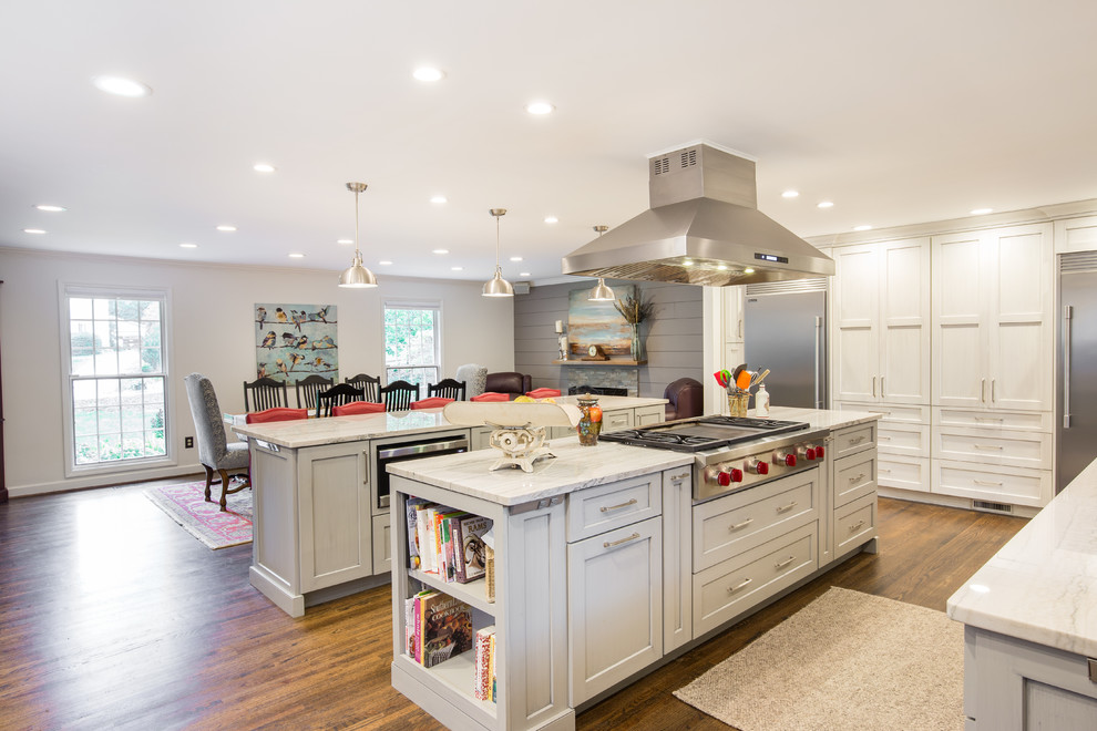 Large transitional single-wall medium tone wood floor and brown floor eat-in kitchen photo with an undermount sink, shaker cabinets, white cabinets, marble countertops, multicolored backsplash, matchstick tile backsplash, stainless steel appliances and two islands