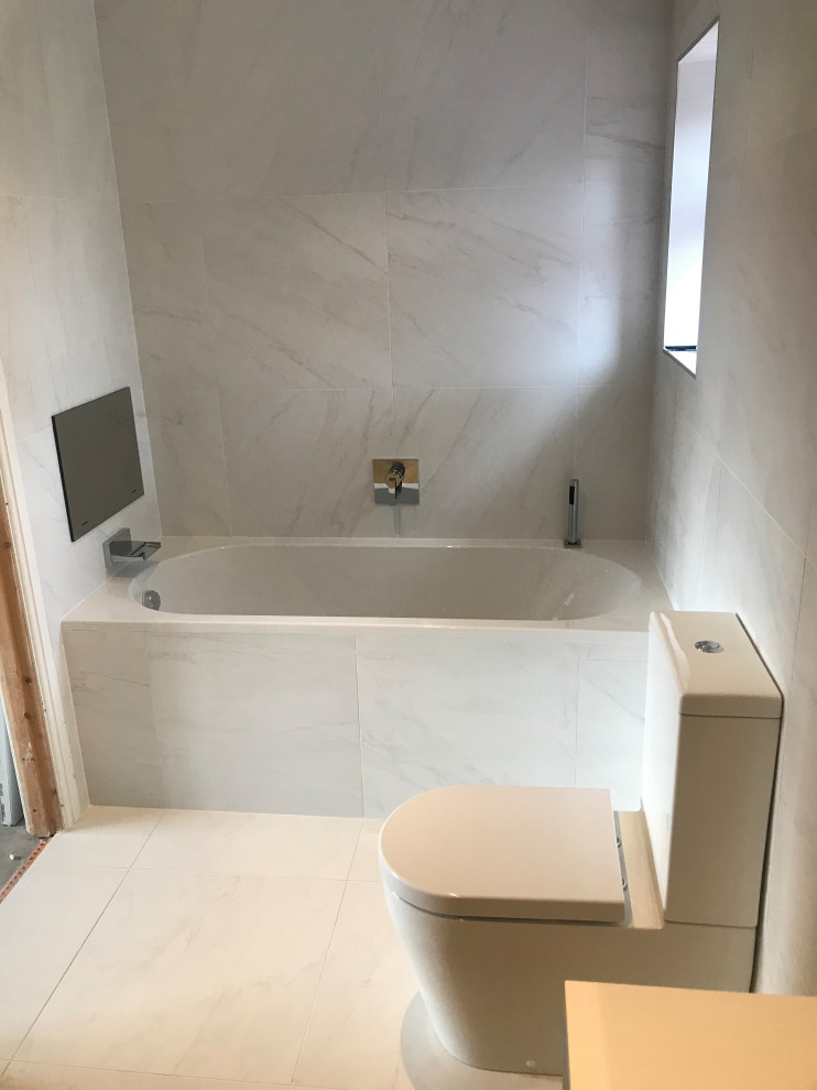 This is an example of a mid-sized modern 3/4 bathroom with black cabinets, a drop-in tub, an open shower, white tile, ceramic tile, white walls, ceramic floors, a wall-mount sink, white floor, an open shower, a single vanity and a floating vanity.