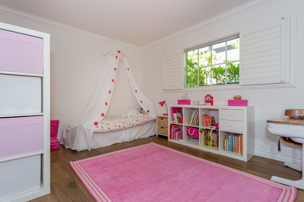 Mid-sized transitional kids' room in Los Angeles with white walls and medium hardwood floors for girls.