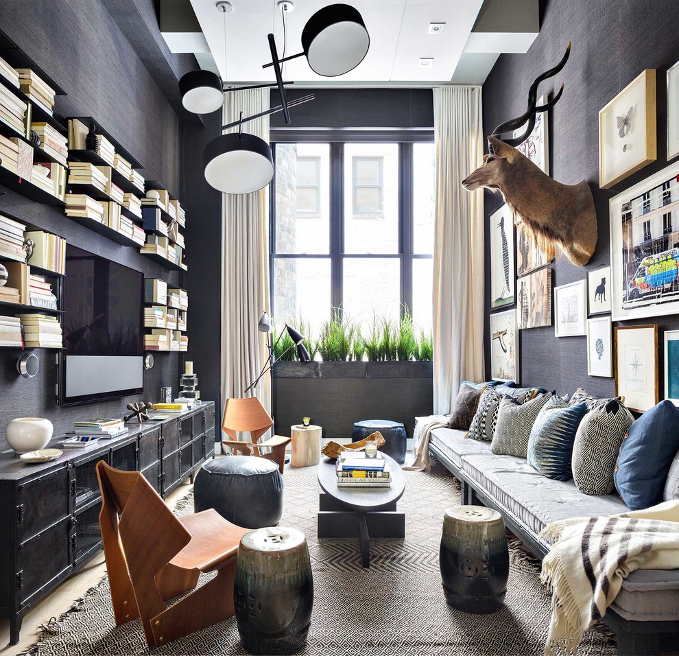 This is an example of an eclectic family room in New York with a library, grey walls, no fireplace and a wall-mounted tv.