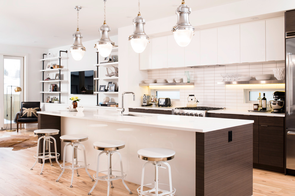 Design ideas for a contemporary galley open plan kitchen in Calgary with an undermount sink, flat-panel cabinets, white cabinets, white splashback, subway tile splashback and stainless steel appliances.