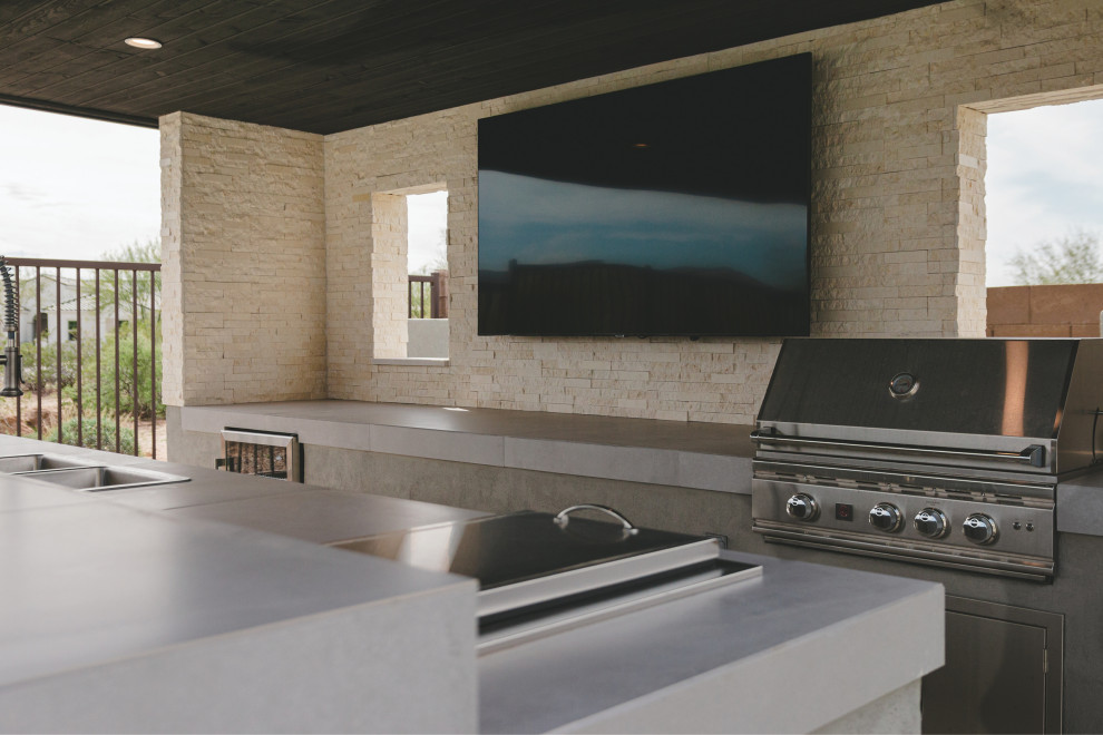 Idées déco pour une terrasse arrière moderne avec une cuisine d'été, des pavés en pierre naturelle et une pergola.