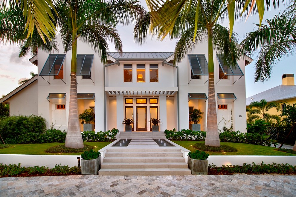 Photo of a tropical two-storey white exterior in Miami with a gable roof.