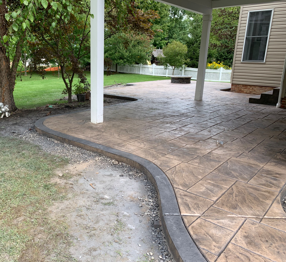 Design ideas for a mid-sized traditional backyard patio in Cleveland with a fire feature, stamped concrete and a roof extension.