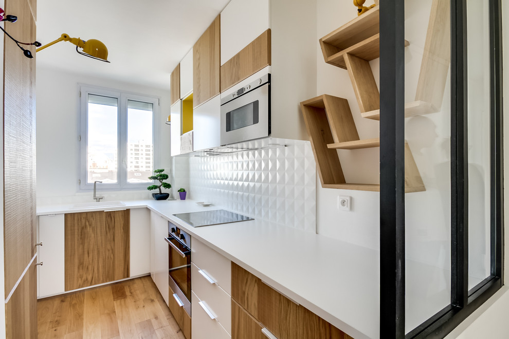 This is an example of a small scandinavian l-shaped separate kitchen in Paris with medium wood cabinets, white splashback, panelled appliances, medium hardwood floors, no island and a drop-in sink.