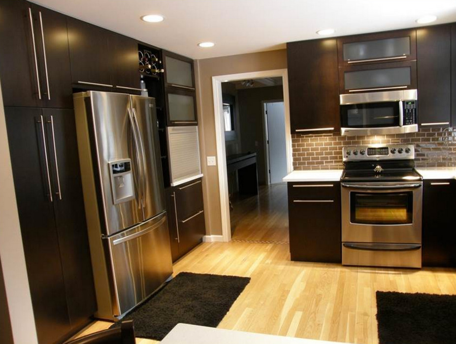 Example of a mid-sized minimalist u-shaped light wood floor enclosed kitchen design with an undermount sink, flat-panel cabinets, dark wood cabinets, quartz countertops, brown backsplash, ceramic backsplash, stainless steel appliances and a peninsula