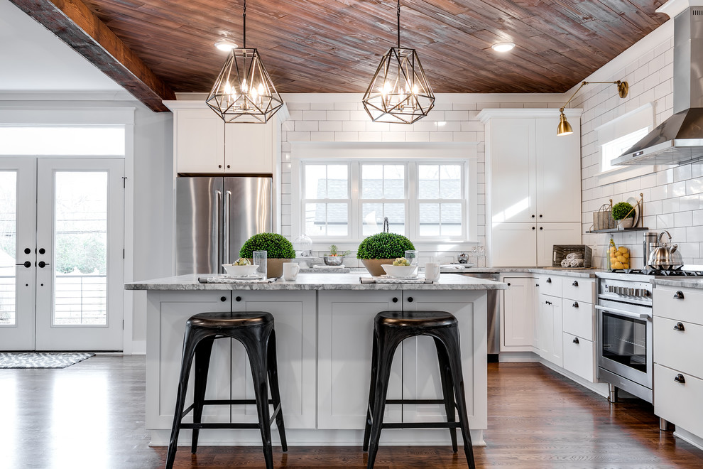 Country l-shaped kitchen in Richmond with shaker cabinets, white cabinets, white splashback, subway tile splashback, stainless steel appliances, dark hardwood floors, with island, brown floor and grey benchtop.