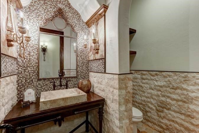 Photo of a mid-sized traditional powder room in Austin with open cabinets, dark wood cabinets, brown tile, mosaic tile, white walls and a vessel sink.