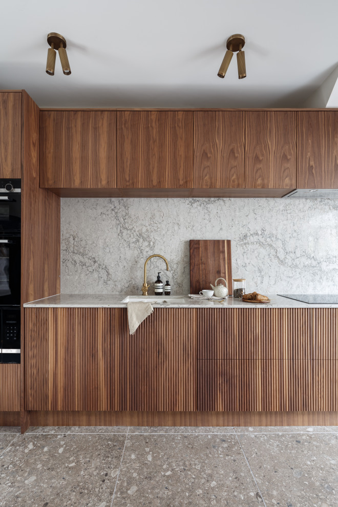 Idéer för att renovera ett mellanstort 50 tals grå grått kök, med en integrerad diskho, släta luckor, skåp i mörkt trä, bänkskiva i kvartsit, grått stänkskydd, integrerade vitvaror, klinkergolv i porslin och brunt golv