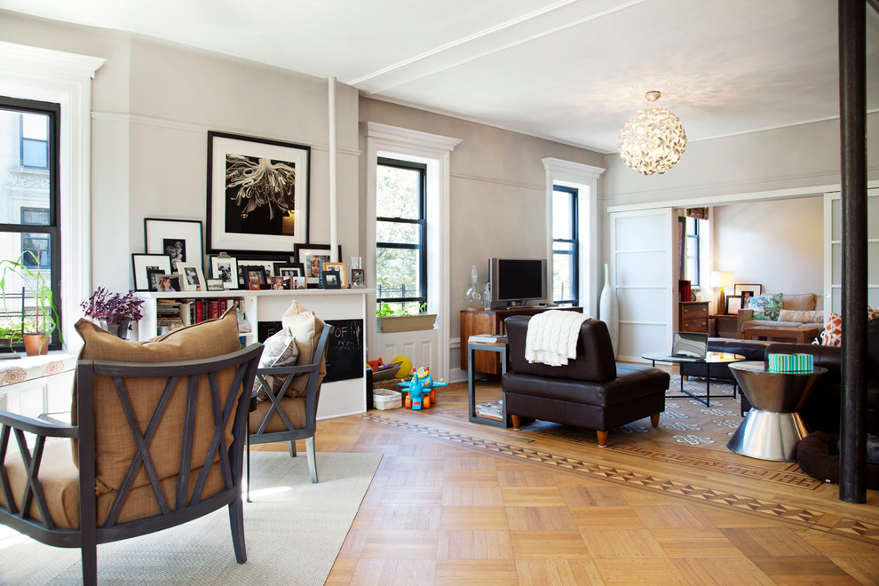 This is an example of a large contemporary open concept living room in New York with grey walls and a freestanding tv.