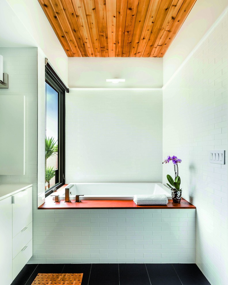 This is an example of a contemporary bathroom in Charlotte with flat-panel cabinets, white cabinets, a drop-in tub, white tile and subway tile.
