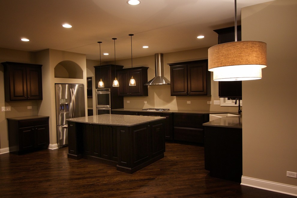 Inspiration for a mid-sized transitional single-wall dark wood floor enclosed kitchen remodel in Chicago with recessed-panel cabinets, white cabinets, solid surface countertops, white backsplash, porcelain backsplash, stainless steel appliances, an island and a farmhouse sink