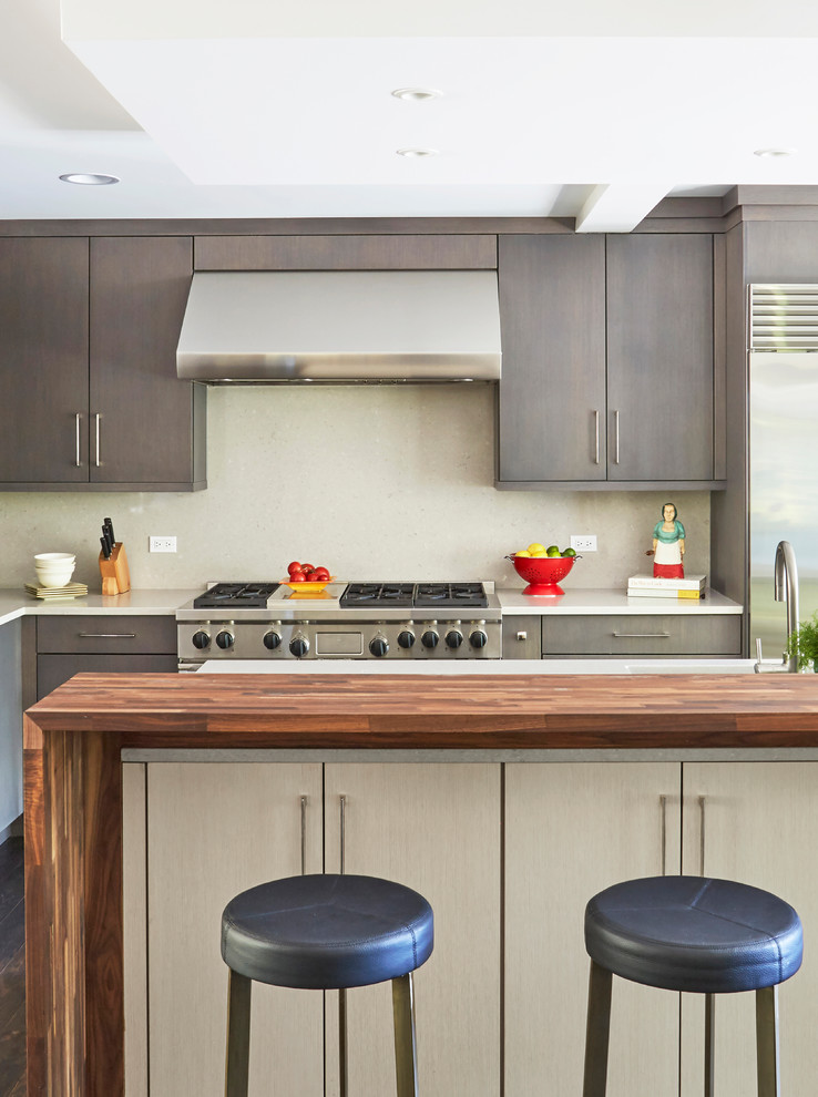 Photo of a large eclectic u-shaped open plan kitchen in Chicago with an undermount sink, flat-panel cabinets, grey cabinets, wood benchtops, beige splashback, stone slab splashback, stainless steel appliances, dark hardwood floors, with island and brown floor.