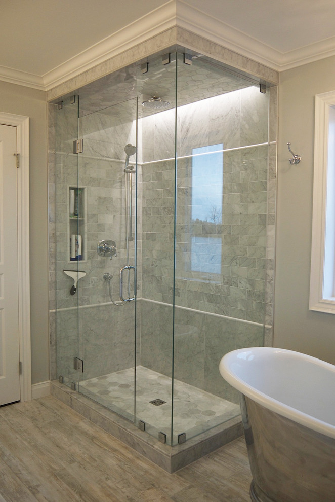 Design ideas for a mid-sized traditional master bathroom in Toronto with an undermount sink, recessed-panel cabinets, white cabinets, marble benchtops, a two-piece toilet, gray tile, stone tile, grey walls, porcelain floors, a corner shower and a freestanding tub.