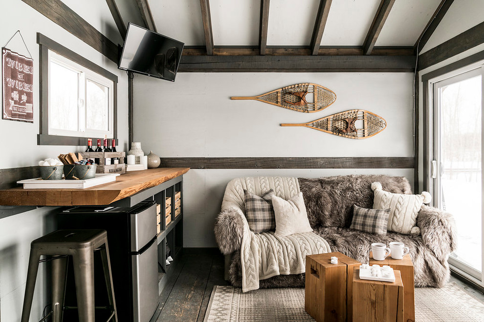 Inspiration for a country family room in Calgary with a home bar, white walls, painted wood floors, a wall-mounted tv and grey floor.