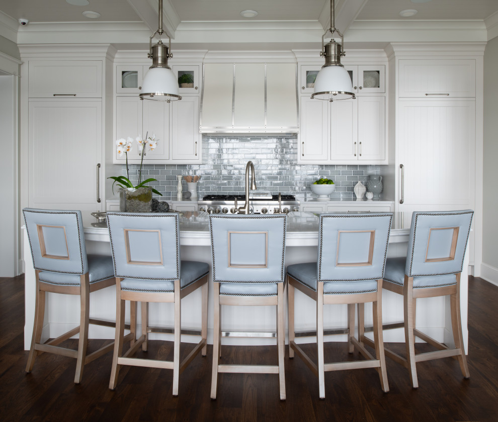 Design ideas for a large beach style galley open plan kitchen in Minneapolis with a farmhouse sink, shaker cabinets, white cabinets, quartzite benchtops, blue splashback, subway tile splashback, panelled appliances, medium hardwood floors, brown floor, white benchtop and timber.