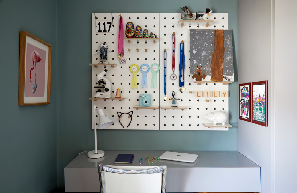 This is an example of a small modern gender neutral children’s room in London with blue walls and carpet.
