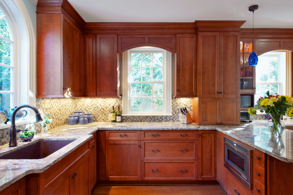 Enclosed kitchen - mid-sized transitional u-shaped medium tone wood floor enclosed kitchen idea with an undermount sink, recessed-panel cabinets, medium tone wood cabinets, granite countertops, multicolored backsplash, mosaic tile backsplash, paneled appliances and a peninsula