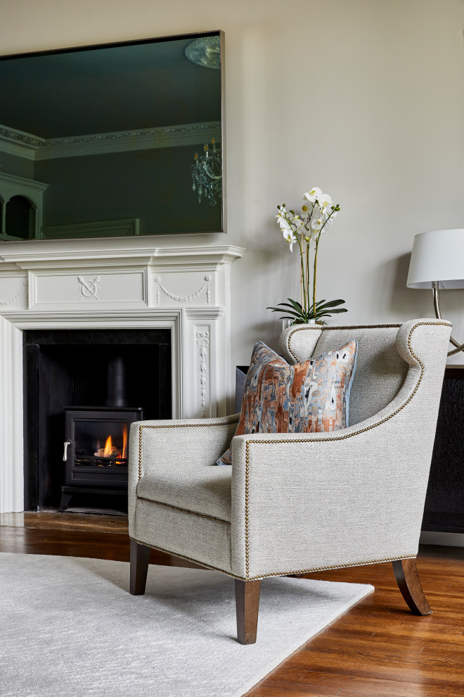 Inspiration for a large traditional formal enclosed living room in West Midlands with beige walls, limestone flooring, a wood burning stove, a wooden fireplace surround, a wall mounted tv and brown floors.