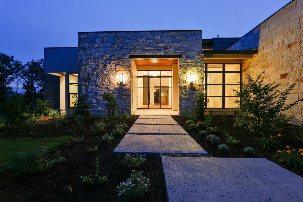 Photo of a large contemporary one-storey grey exterior in Austin with stone veneer.