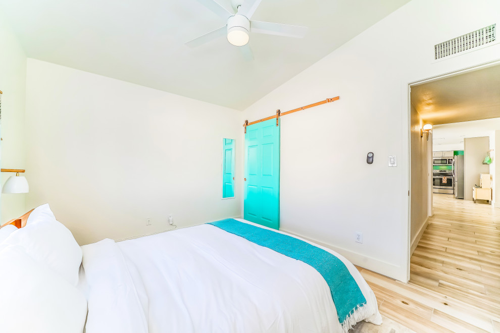Photo of a mid-sized contemporary guest bedroom in Phoenix with white walls, plywood floors, beige floor and vaulted.