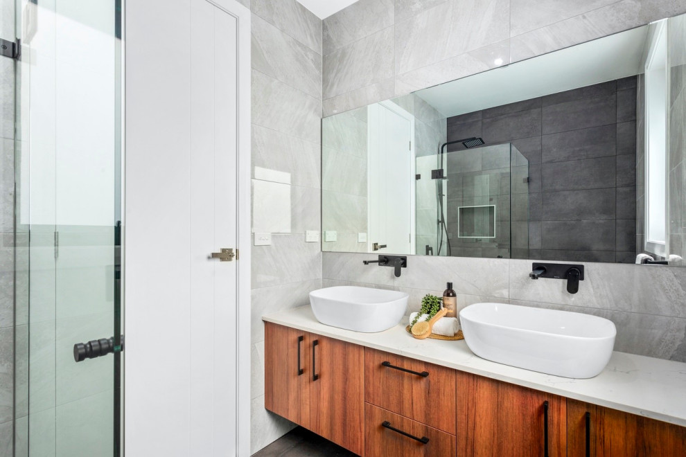 Photo of a small industrial 3/4 bathroom in Sydney with flat-panel cabinets, orange cabinets, a corner shower, gray tile, porcelain tile, grey walls, ceramic floors, a vessel sink, engineered quartz benchtops, grey floor, a hinged shower door, white benchtops, a double vanity and a floating vanity.