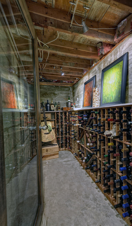 Small eclectic wine cellar in Other with concrete floors and storage racks.
