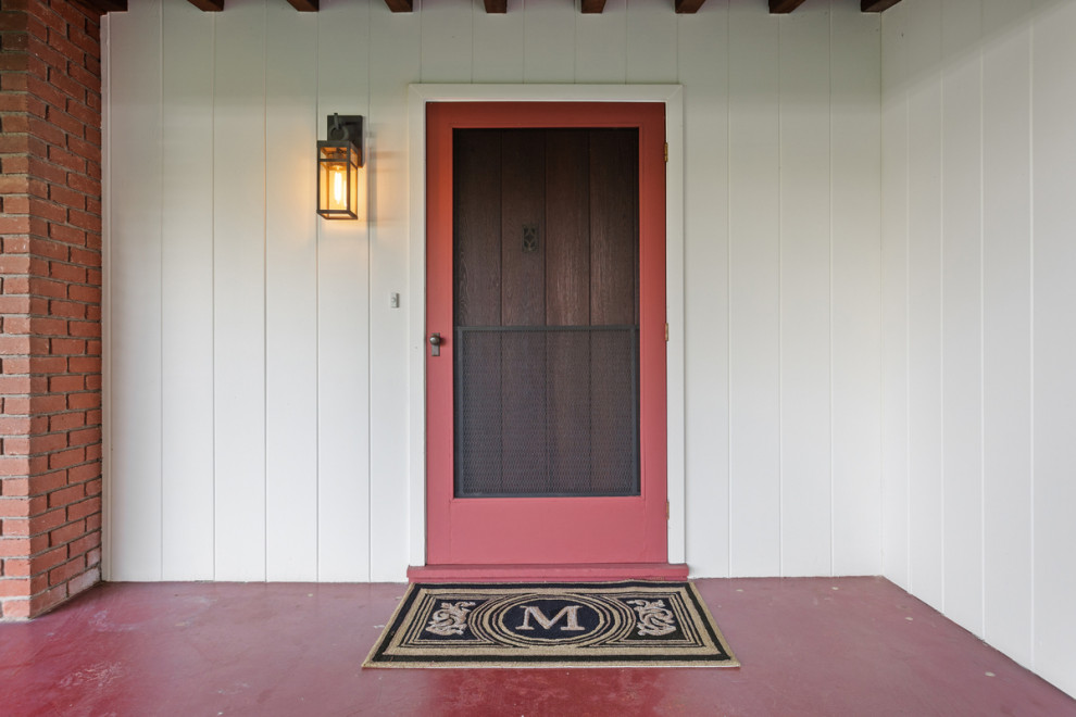 Ejemplo de puerta principal de estilo americano extra grande con paredes blancas, suelo de cemento, puerta simple, puerta de madera oscura, suelo rojo, vigas vistas y madera