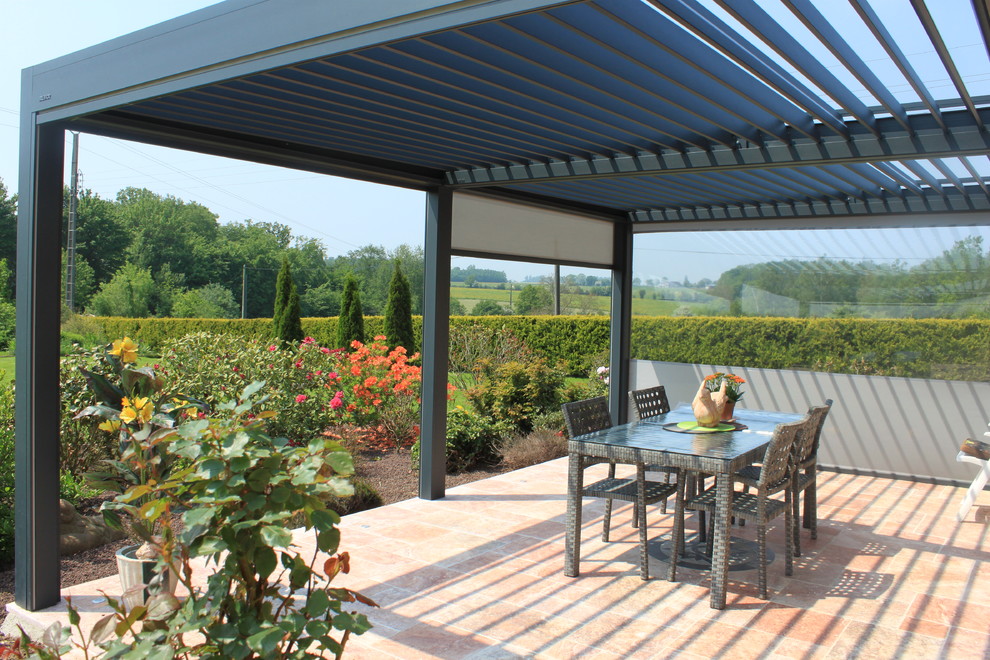 This is an example of a mid-sized contemporary patio in Lille with tile and a pergola.