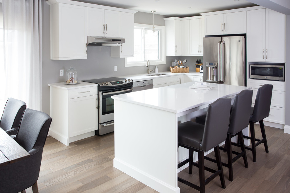 Photo of a mid-sized traditional l-shaped eat-in kitchen in Toronto with a double-bowl sink, shaker cabinets, white cabinets, quartz benchtops, stainless steel appliances, dark hardwood floors, with island and beige floor.