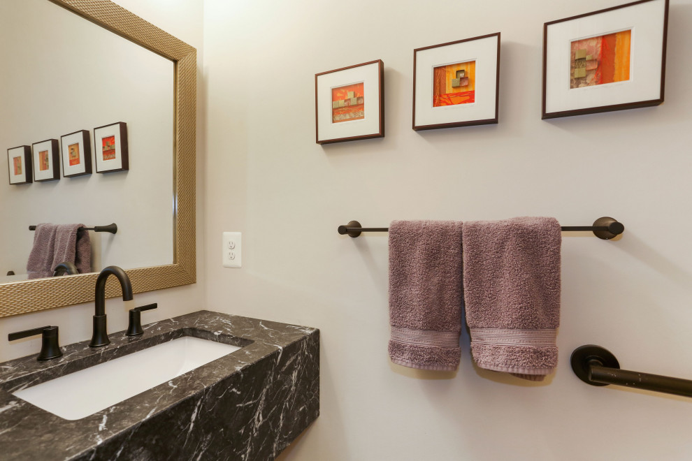 Example of a small transitional single-sink, medium tone wood floor and brown floor bathroom design in DC Metro with black cabinets, a two-piece toilet, an integrated sink, granite countertops, black countertops, a floating vanity and beige walls