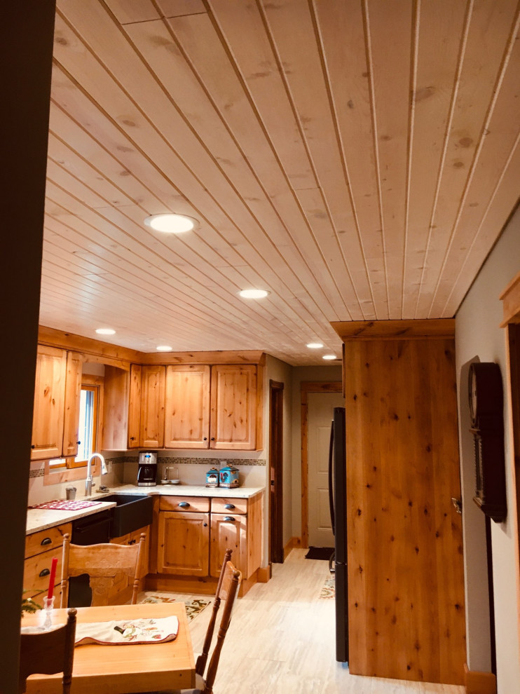 Example of a mid-sized mountain style u-shaped enclosed kitchen design with a farmhouse sink, raised-panel cabinets, light wood cabinets, quartz countertops and an island
