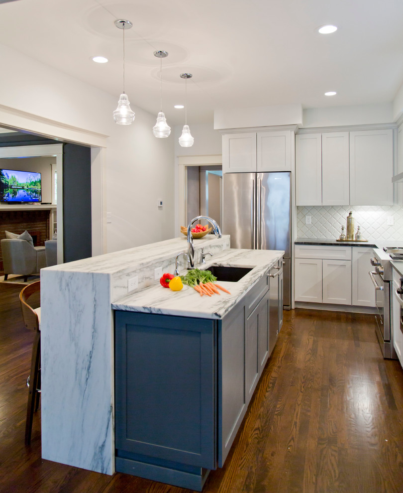Design ideas for a large transitional l-shaped separate kitchen in St Louis with a drop-in sink, recessed-panel cabinets, white cabinets, marble benchtops, white splashback, ceramic splashback, stainless steel appliances, medium hardwood floors and with island.