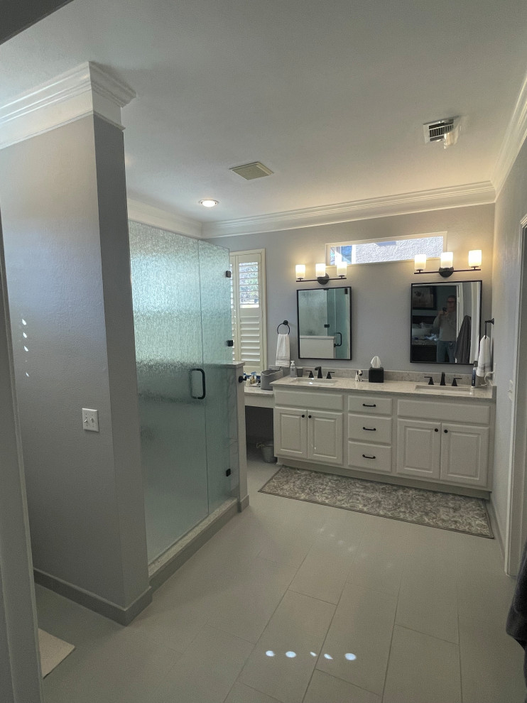 Large contemporary ensuite bathroom in Austin with raised-panel cabinets, white cabinets, an alcove shower, a two-piece toilet, white tiles, porcelain tiles, grey walls, porcelain flooring, a submerged sink, grey floors, a hinged door, grey worktops, a wall niche, double sinks and a built in vanity unit.
