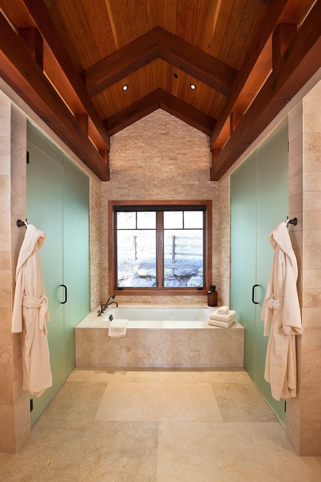Inspiration for a mid-sized country master bathroom in Denver with an undermount tub, an alcove shower, beige tile, stone slab and limestone floors.